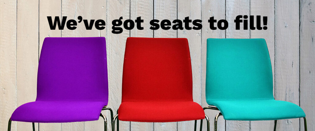 A photograph of three empty seats, one purple, one red, and one blue. Text says "We've got seats to fill!"